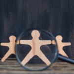 Marketing analysis concept with magnifying glass over wooden figure on wooden and grunge background close-up. October 2023 start-up fundraising news